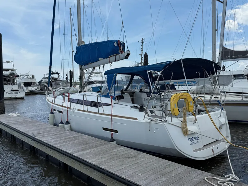 Slide: The Image of 2015 Jeanneau 409 sailboat docked at marina, featuring blue canopy and white hull. - 3