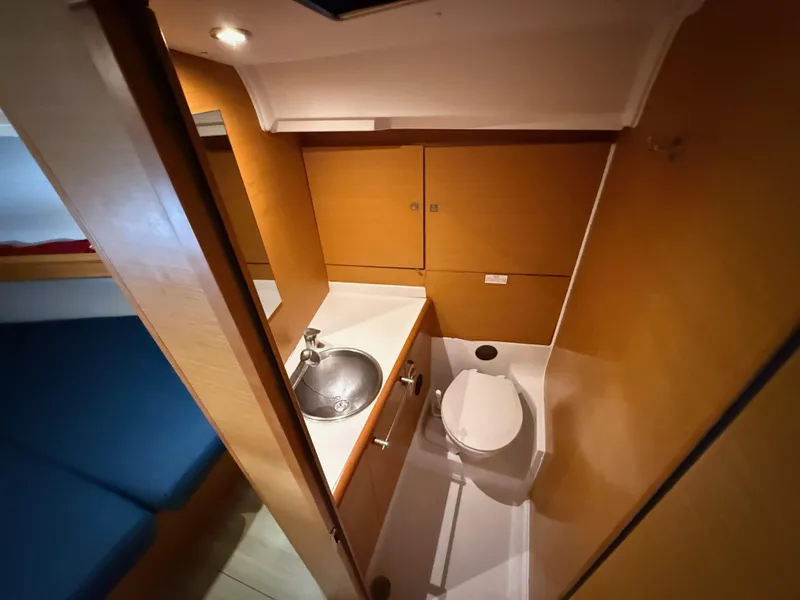Slide: The Image of 2015 Jeanneau 409 yacht bathroom with sink, toilet, and wooden cabinetry. - 30