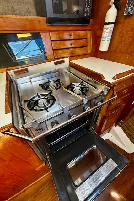 Slide: The Image of 1986 Hunter Legend 45 yacht kitchen with stove and oven, wooden cabinetry, and fire extinguisher. - 33
