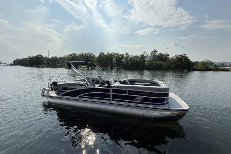 The Image of 2026 Bennington M Quad Bench 24 MFB pontoon boat on a serene lake. - 2