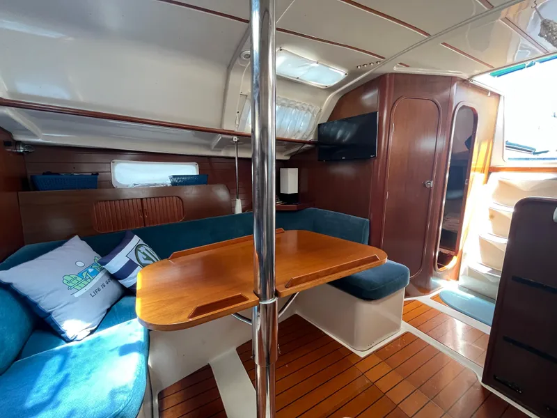 Slide: The Image of Interior of 1998 Beneteau 321 sailboat with wooden table and blue seating. - 22