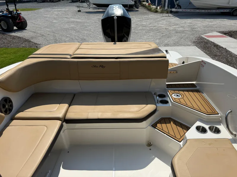 Slide: The Image of 2019 Sea Ray 21SPX boat interior with tan seating and cup holders, docked outdoors. - 18