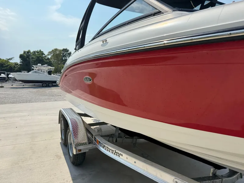 Slide: The Image of 2019 Sea Ray 21SPX boat with red hull on a trailer, parked outdoors. - 2