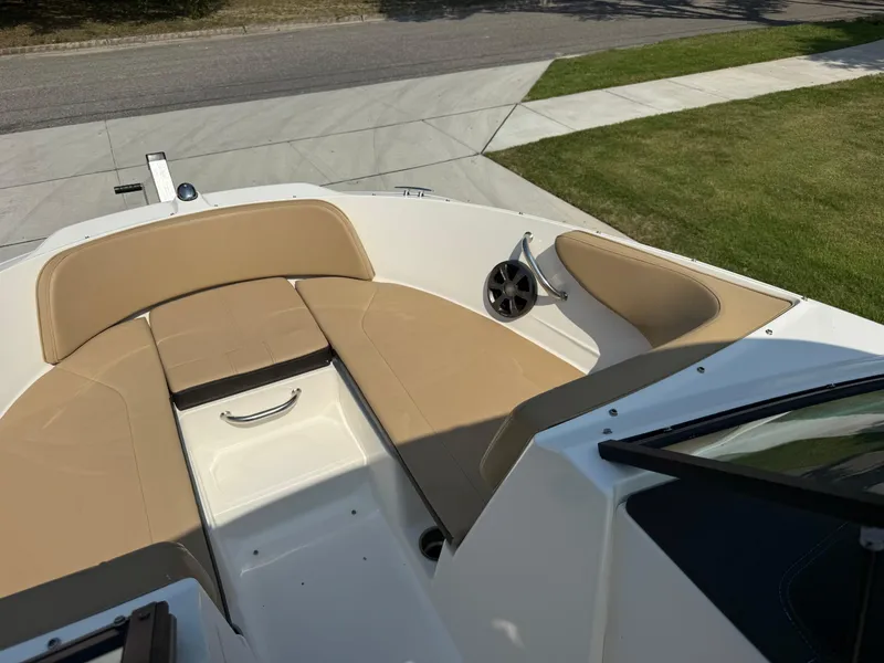 Slide: The Image of 2019 Sea Ray 21SPX boat interior with tan seating and speaker, parked on driveway. - 9