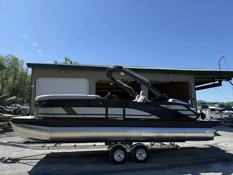 The Image of 2026 Bennington M Swingback 24 MSB pontoon boat on trailer, parked outside a garage. - 0