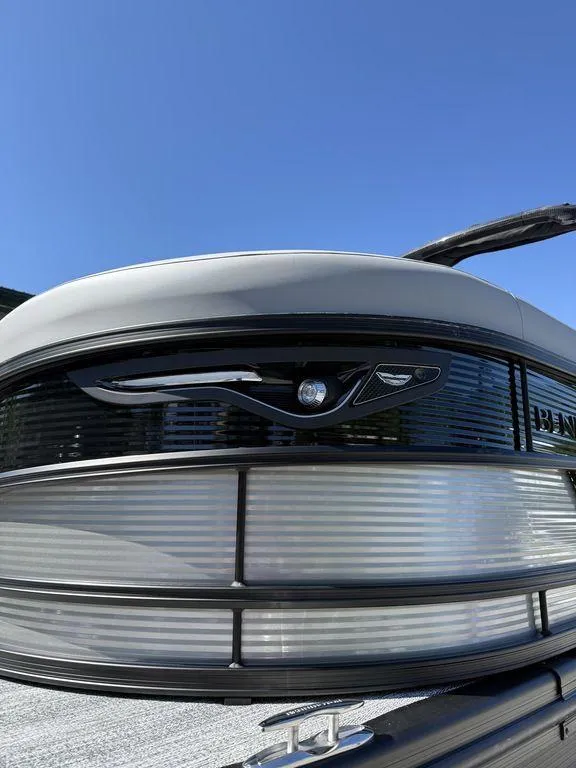 Slide: The Image of 2026 Bennington M Swingback 24 MSB pontoon boat front view under clear blue sky. - 3
