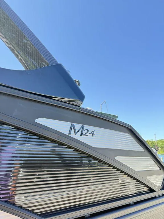 Slide: The Image of 2026 Bennington M Swingback 24 MSB pontoon boat on trailer, surrounded by trees. - 7