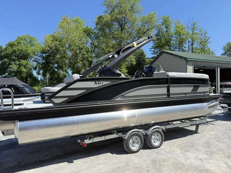 Slide: The Image of 2026 Bennington M Swingback 24 MSB pontoon boat with ladder, parked outdoors. - 8