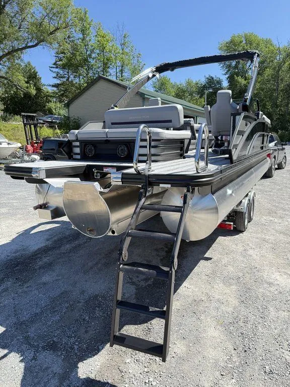 Slide: The Image of 2026 Bennington M Swingback 24 MSB boat deck with ladder, parked on gravel. - 9