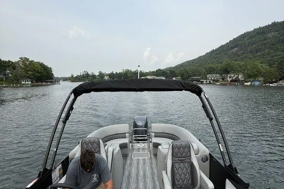 Slide: The Image of 2026 Bennington RX Sport Quad Bench 23 RXFB on a scenic lake with lush hills. - 15