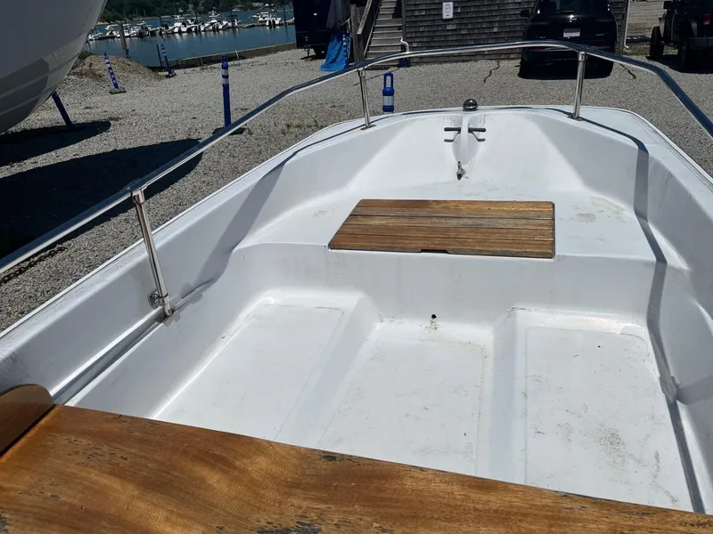 Slide: The Image of 1991 Boston Whaler 13 boat interior with wooden seats, docked near marina. - 5