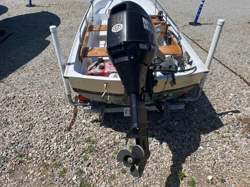 Slide: The Image of 1991 Boston Whaler 13 boat with outboard motor on gravel surface. - 7