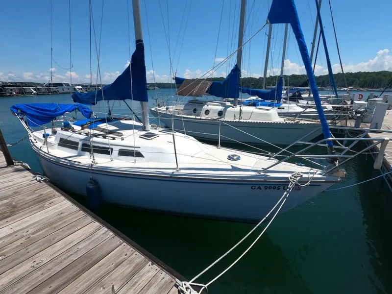 The Image of 1985 Catalina 27 sailboat docked at marina, blue covers, clear sky, calm water. - 0