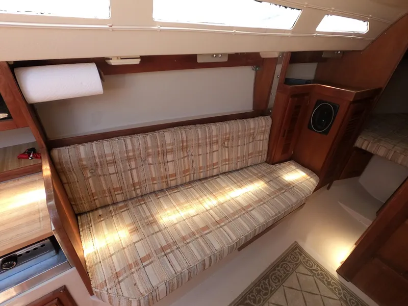 Slide: The Image of Interior of a 1985 Catalina 27 sailboat with a plaid cushioned bench. - 14
