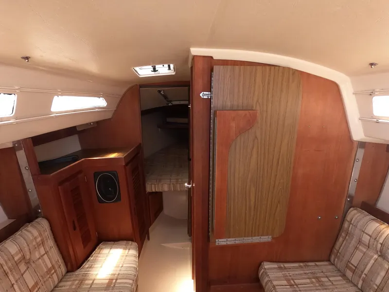 Slide: The Image of Interior of a 1985 Catalina 27 sailboat with wood paneling and plaid seating. - 15