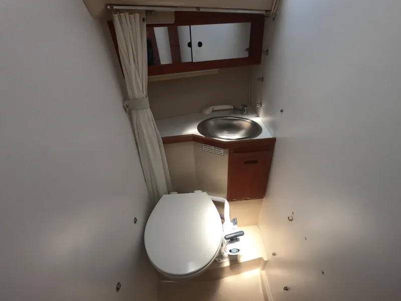 Slide: The Image of Compact bathroom in a 1985 Catalina 27 sailboat, featuring a toilet, sink, and storage cabinet. - 16