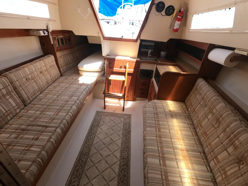 Slide: The Image of Interior of a 1985 Catalina 27 sailboat with cozy seating and compact kitchen area. - 18