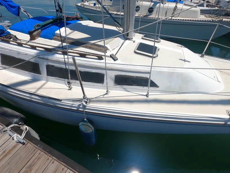 Slide: The Image of 1985 Catalina 27 sailboat docked, featuring white deck and blue accents. - 19