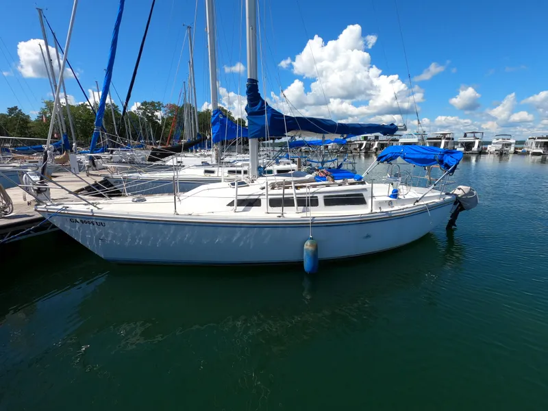 Slide: The Image of 1985 Catalina 27 sailboat docked in a marina under a clear blue sky. - 2