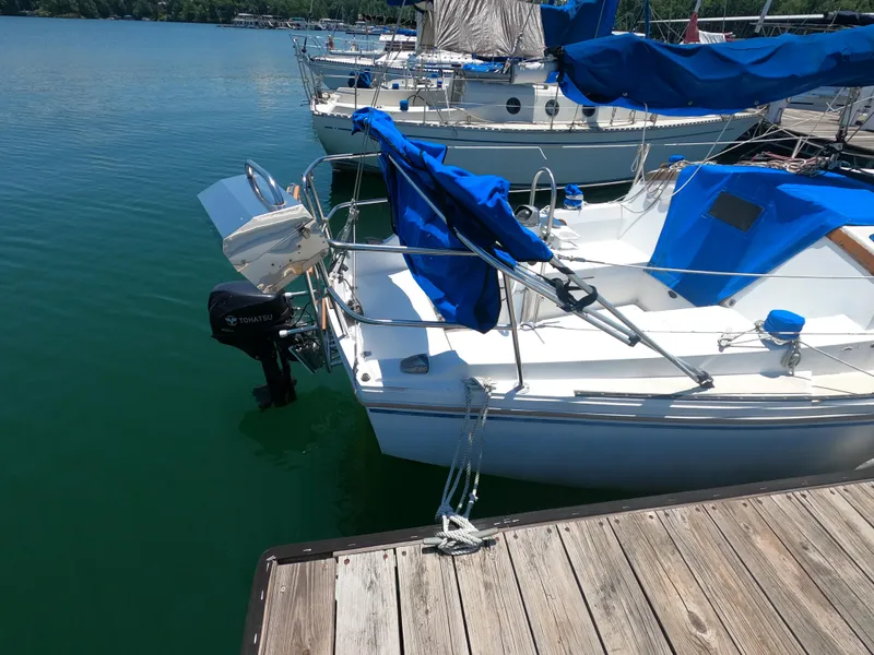 Slide: The Image of 1985 Catalina 27 sailboat docked with blue covers and Tohatsu outboard motor. - 3