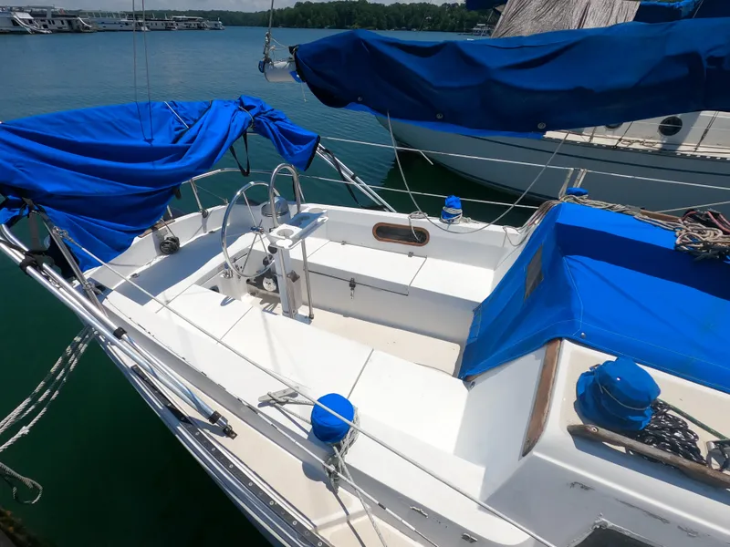 Slide: The Image of 1985 Catalina 27 sailboat with blue covers docked on calm water. - 5