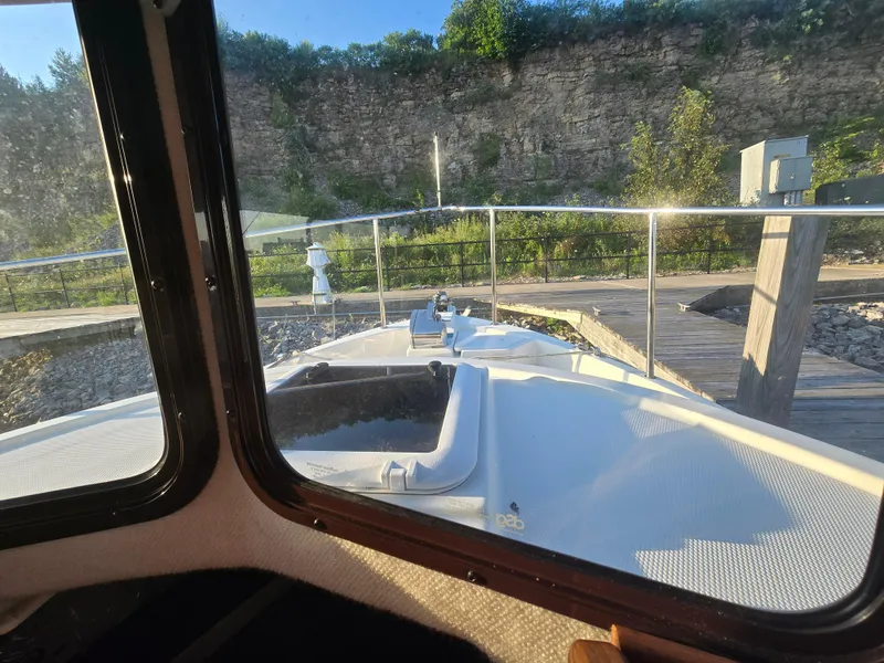 Slide: The Image of 2017 Ranger Tugs R-27 boat docked, viewed from cabin window, with rocky cliff background. - 25