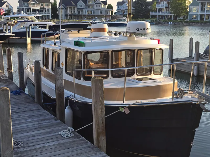 Slide: The Image of 2017 Ranger Tugs R-27 docked at a marina with waterfront homes in the background. - 3