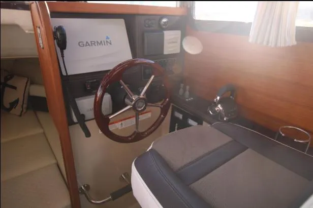 Slide: The Image of 2017 Ranger Tugs R-27 helm with Garmin navigation, wooden steering wheel, and comfortable seating. - 31