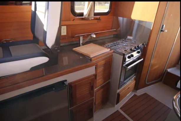 Slide: The Image of 2017 Ranger Tugs R-27 interior kitchen with stove, sink, and wooden cabinetry. - 34