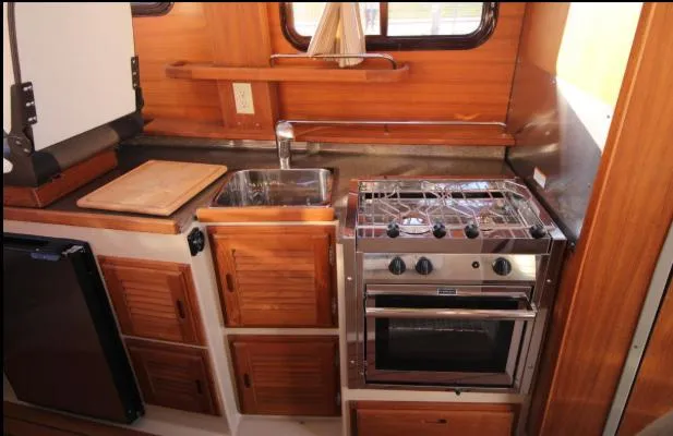Slide: The Image of 2017 Ranger Tugs R-27 kitchen with stove, sink, and wooden cabinetry. - 35