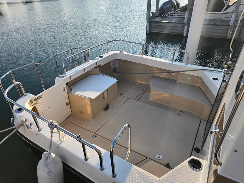 Slide: The Image of 2017 Ranger Tugs R-27 boat deck with seating and storage, docked by the water. - 4