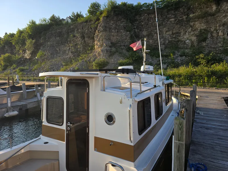 Slide: The Image of 2017 Ranger Tugs R-27 docked by rocky shoreline with American flag. - 6