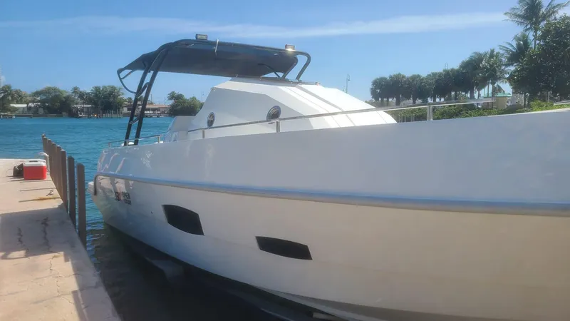 Slide: The Image of Giupex 33 boat docked by the water, 2021 model, sunny day, palm trees in background. - 2