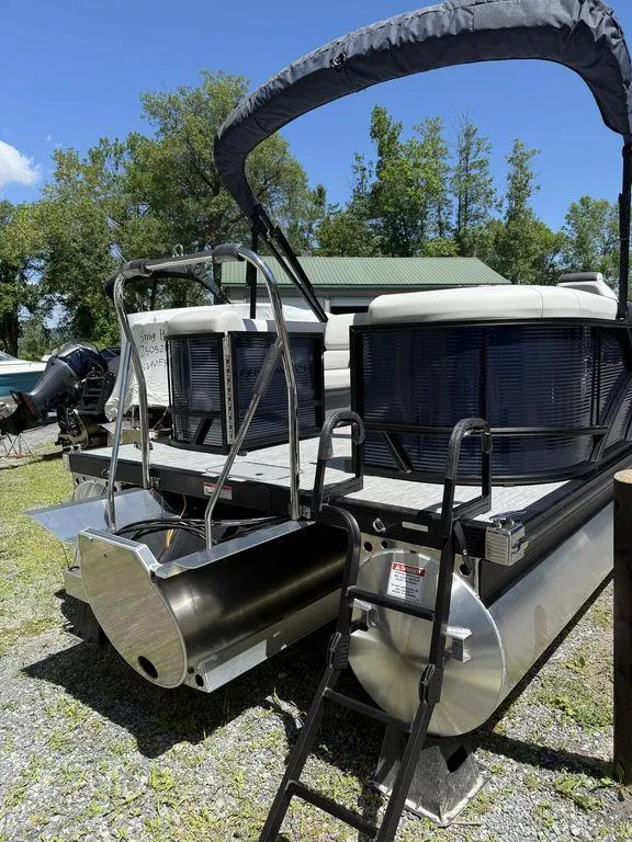 Slide: The Image of 2026 Bennington S Quad Bench 22 SSR pontoon boat with ladder and canopy, parked outdoors. - 5