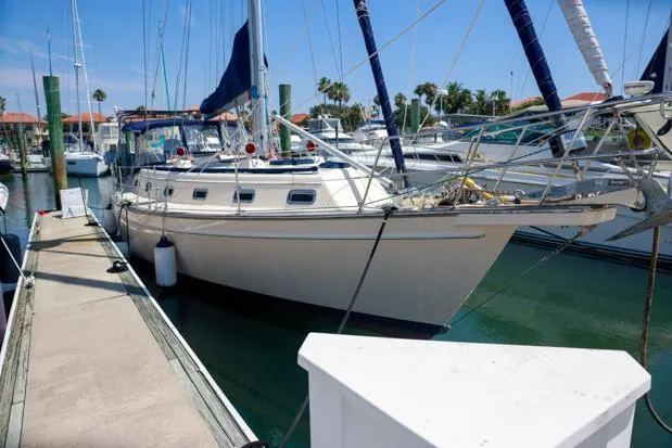 The Image of 1998 Island Packet 40 sailboat docked at marina under clear blue sky. - 1