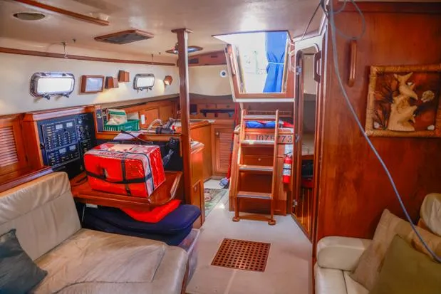 Slide: The Image of Interior of a 1998 Island Packet 40 sailboat, featuring cozy seating and wooden finishes. - 14