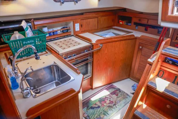 Slide: The Image of 1998 Island Packet 40 yacht kitchen with sink, stove, and wooden cabinetry. - 15