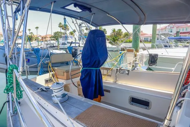 Slide: The Image of 1998 Island Packet 40 sailboat cockpit with covered equipment, docked in a marina. - 7