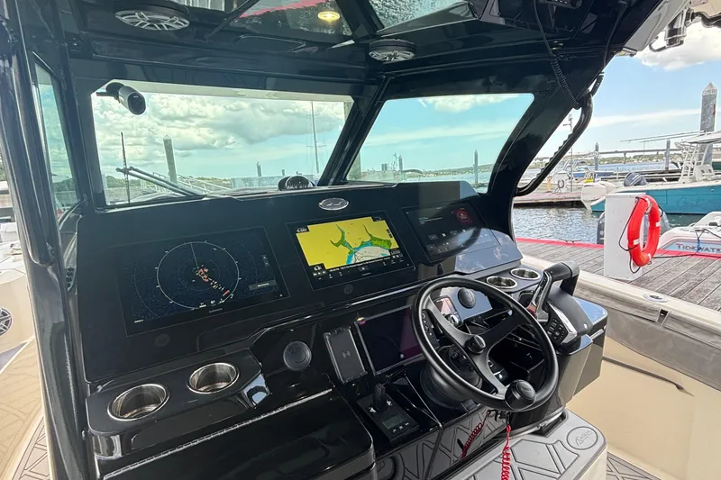 Slide: The Image of 2024 Scout 377 LXF boat dashboard with navigation screens and steering wheel at marina. - 12