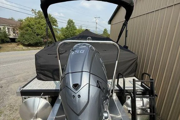 Slide: The Image of 2026 Bennington S Swingback 22 SSB pontoon boat with powerful outboard motor, docked near a building. - 10