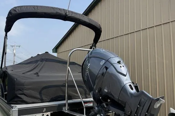 Slide: The Image of 2026 Bennington S Swingback 22 SSB pontoon boat with outboard motor, docked near a building. - 4