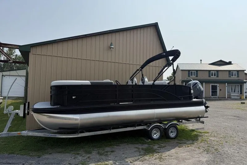 Slide: The Image of 2026 Bennington S Swingback 22 SSB pontoon boat on trailer, parked near a building. - 6