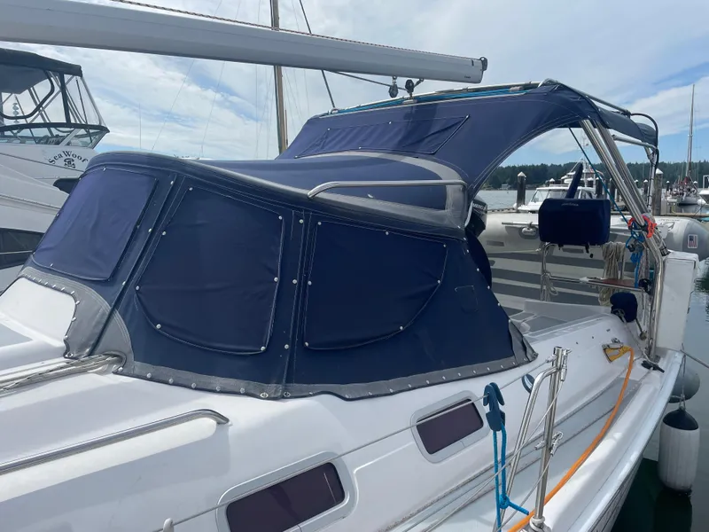 Slide: The Image of 2004 Hunter 36 sailboat with blue canvas cover docked at marina. - 2