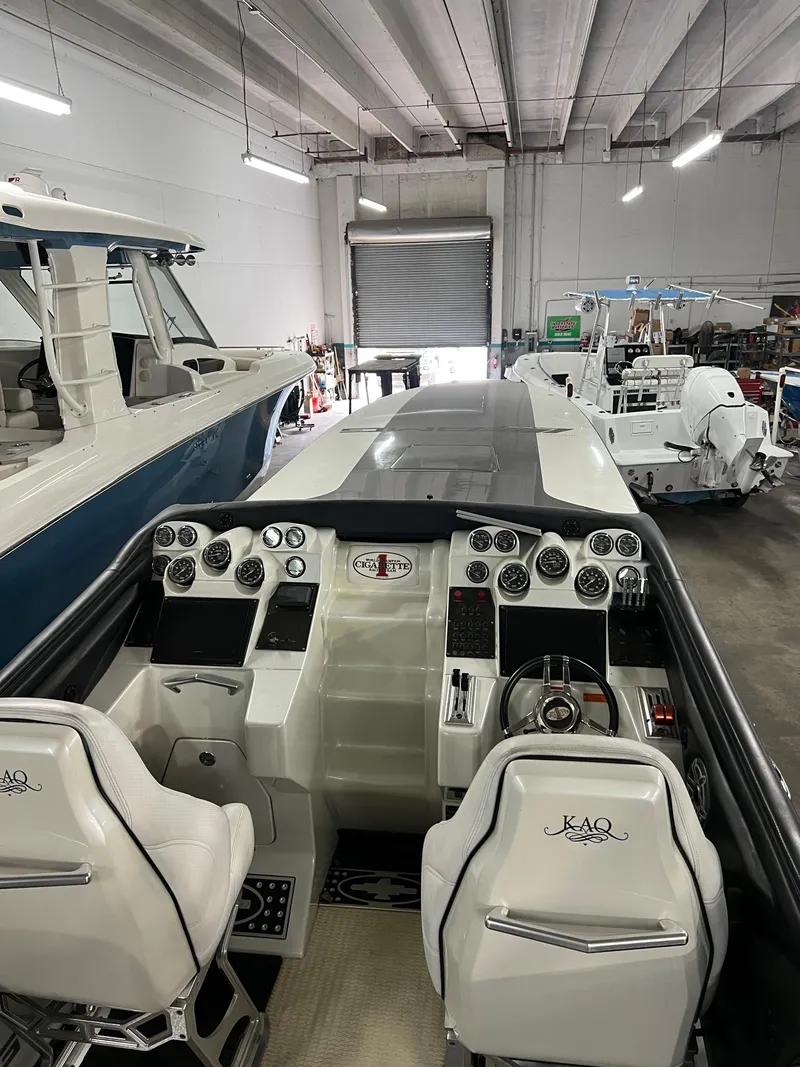 Slide: The Image of 2012 Cigarette 50' Marauder AMG boat interior with sleek dashboard and seating in a garage. - 4
