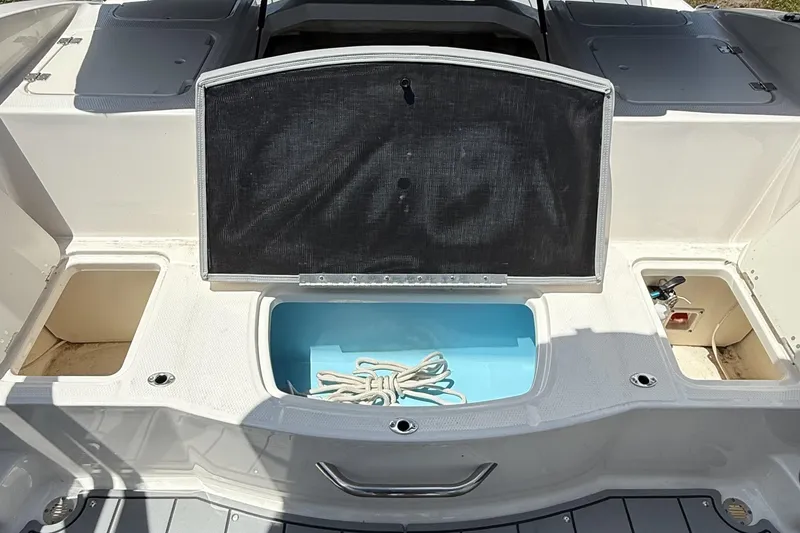 Slide: The Image of 2022 Chaparral 21 SSi OB boat storage compartments with open lids and visible rope. - 17
