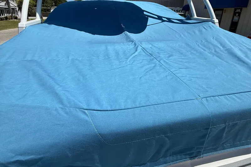 Slide: The Image of 2022 Chaparral 21 SSi OB boat with blue cover, outdoor setting. - 20