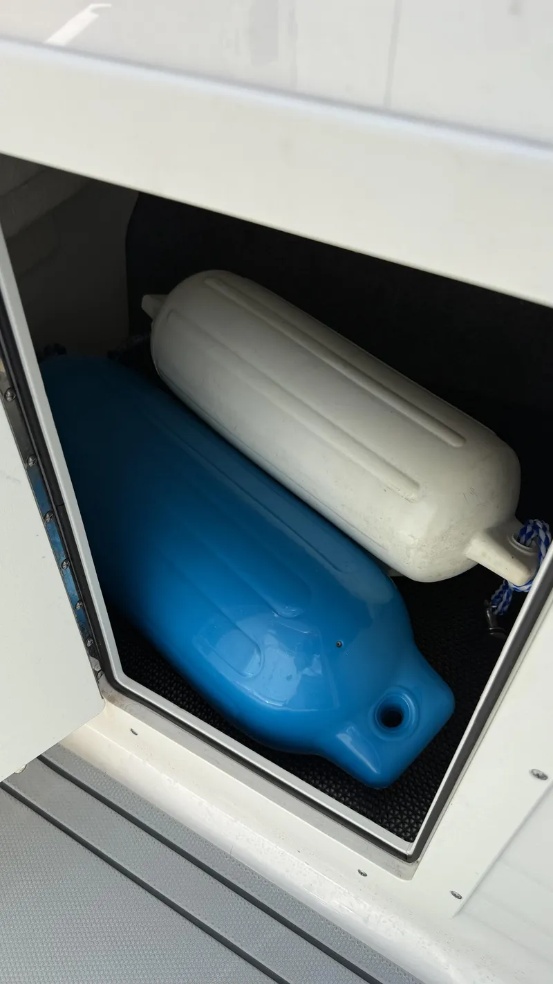 Slide: The Image of Storage compartment with blue and white boat fenders on a 2022 Chaparral 21 SSi OB. - 24