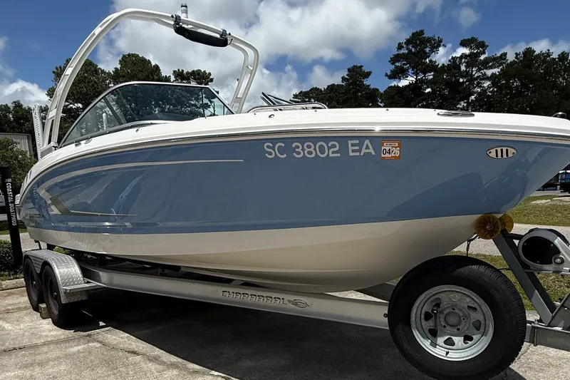 Slide: The Image of 2022 Chaparral 21 SSi OB boat on trailer, blue and white design, parked outdoors. - 4