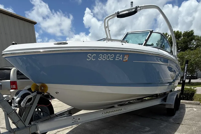 Slide: The Image of 2022 Chaparral 21 SSi OB boat on trailer, blue and white design, parked outdoors. - 5