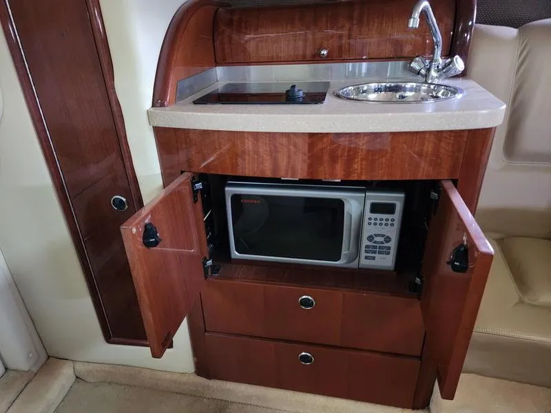 Slide: The Image of 2006 Cobalt 323 boat interior with kitchenette, featuring a sink, stove, and microwave. - 5